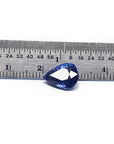 Deep blue pear-cut natural sapphire gemstone next to a ruler, showing its size and brilliant facets.