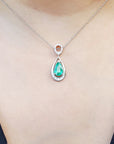 Emerald teardrop pendant necklace on a person wearing a dark blue top.