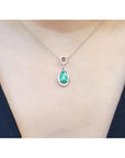 Emerald teardrop pendant necklace on a person wearing a dark blue top.