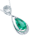 A 14k white gold necklace with a teardrop natural colombian emerald pendant on a white background.