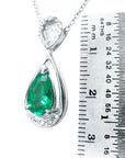Teardrop-shaped emerald pendant with white gold chain on a ruler for scale
