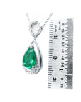 Teardrop-shaped emerald pendant with white gold chain on a ruler for scale