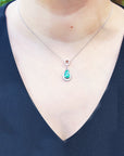 Necklace with a natural emerald pendant on a person wearing a black top.