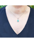 Necklace with a natural emerald pendant on a person wearing a black top.