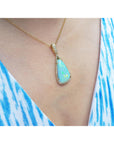 Opal pendant necklace on a person wearing a blue and white striped garment.