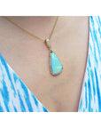 Opal pendant necklace on a person wearing a blue and white striped garment.