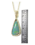 8.05 ct pear-shaped Australian opal pendant with diamond halo and 18K yellow gold chain, shown with ruler.