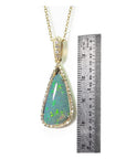 8.05 ct pear-shaped Australian opal pendant with diamond halo and 18K yellow gold chain, shown with ruler.