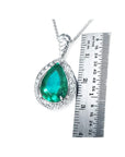 Pear-shaped Colombian emerald pendant with diamond halo in 14K white gold, shown next to a ruler.