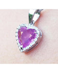 Heart-shaped natural sapphire pendant halo diamond in white gold close-up view on woman's neck