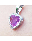 Heart-shaped natural sapphire pendant halo diamond in white gold close-up view on woman's neck