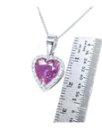 Heart-cut natural pink sapphire pendant with diamond halo on an 18K white gold chain, next to a ruler.