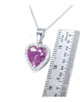 Heart-cut natural pink sapphire pendant with diamond halo on an 18K white gold chain, next to a ruler.