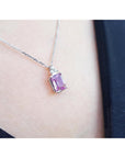 Pink natural sapphire gemstone necklace on a person's neck against a dark background