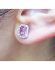 Close-up of a pink sapphire stud earring halo diamond worn on an ear.