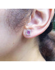Close-up of an ear wearing a pink sapphire earring with a blurred background