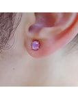 Close-up of an ear wearing a pink star sapphire earring.