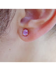 Close-up of an ear wearing a pink star sapphire earring.