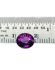 2.59 ct natural intense vivid purple-pink oval cut sapphire gemstone next to a ruler.