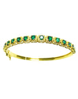 A 14k gold bangle bracelet with round cut natural colombian emeralds brilliant cut sparkling bluish green color.