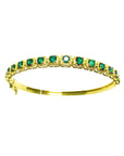 A 14k gold bangle bracelet with round cut natural colombian emeralds brilliant cut sparkling bluish green color.