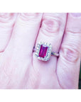 Women's 14K white gold ring with an emerald-cut deep red ruby and diamond halo.