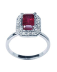 14K white gold ring with an emerald-cut deep red ruby haloed by sparkling diamonds.
