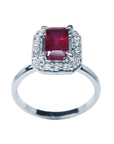 14K white gold ring with an emerald-cut deep red ruby haloed by sparkling diamonds.