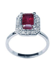 14K white gold ring with an emerald-cut deep red ruby haloed by sparkling diamonds.