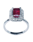 14K white gold ring with an emerald-cut deep red ruby haloed by sparkling diamonds.