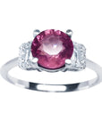 Round cut pinkish-red ruby ring with diamond accents, prong set in 14k white gold.