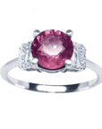 Round cut pinkish-red ruby ring with diamond accents, prong set in 14k white gold.