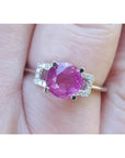 Round cut pinkish-red ruby ring with accented diamonds in 14k white gold.