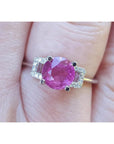 Round cut pinkish-red ruby ring with accented diamonds in 14k white gold.