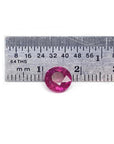 1.64 carat natural round cut ruby with vibrant medium red hue, shown next to a ruler for scale.