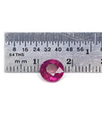 1.64 carat natural round cut ruby with vibrant medium red hue, shown next to a ruler for scale.