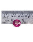 1.64 carat natural round cut ruby with vibrant medium red hue, shown next to a ruler for scale.