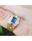 Gold ring with a blue sapphire gemstone on a finger