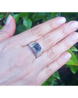 Men's 18K white gold ring with a 5.76 ct vivid blue emerald-cut sapphire in a bezel setting.