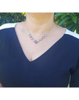 Woman wearing an 18K white gold necklace with tri-colored topaz X-cluster links.