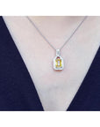 Emerald cut yellow sapphire halo diamond pendant on an 18K white gold chain, worn on a woman.