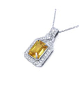 Emerald cut yellow sapphire pendant with halo diamonds on an 18K white gold chain.