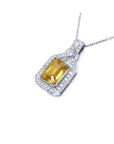 Emerald cut yellow sapphire pendant with halo diamonds on an 18K white gold chain.