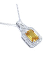 Emerald cut yellow sapphire pendant with diamond halo on an 18K white gold chain.