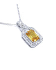 Emerald cut yellow sapphire pendant with diamond halo on an 18K white gold chain.
