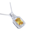 Emerald cut yellow sapphire pendant with diamond halo on an 18K white gold chain.