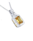 Emerald cut yellow sapphire pendant with halo diamonds in 18K white gold.