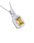 Emerald cut yellow sapphire pendant with halo diamonds in 18K white gold.