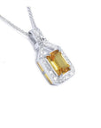 Emerald cut yellow sapphire pendant with halo diamonds in 18K white gold.