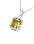 6.01 ct. emerald cut yellow sapphire pendant with diamond halo in 18K white gold.